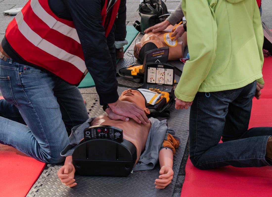 zwei Personen üben Reanimation an einer Puppe